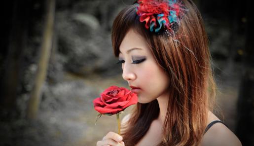 Mujer japonesa sosteniendo una rosa roja